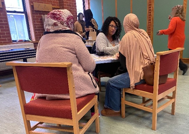 Two Afghan women speaking to another woman at the event.