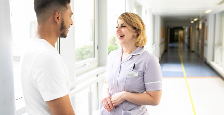 Nurse and patient chatting in hospital corridor 
