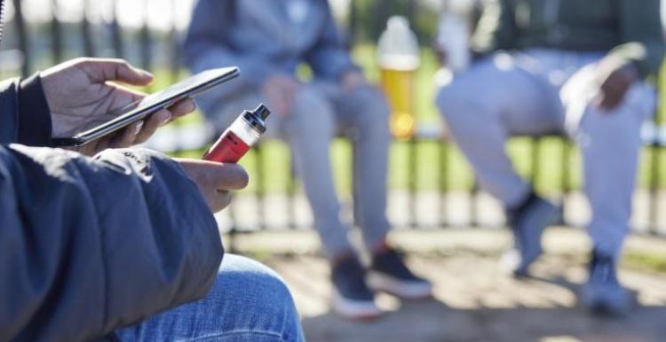 Young person on their phone whilst vaping
