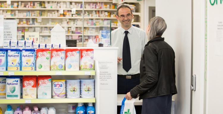 Woman at counter of a pharmacy talking to a pharmacist