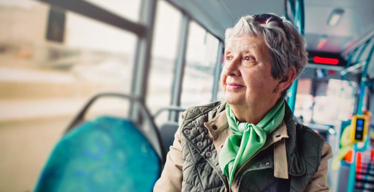 Elderly woman sitting on a bus looking out the window