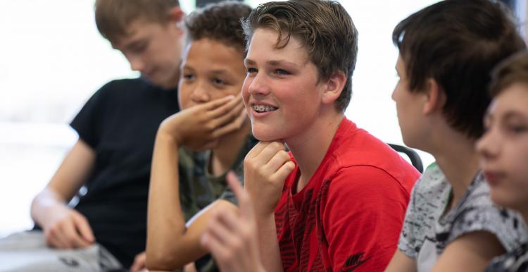Group of young teenage schoolboys sitting down, talking and smiling