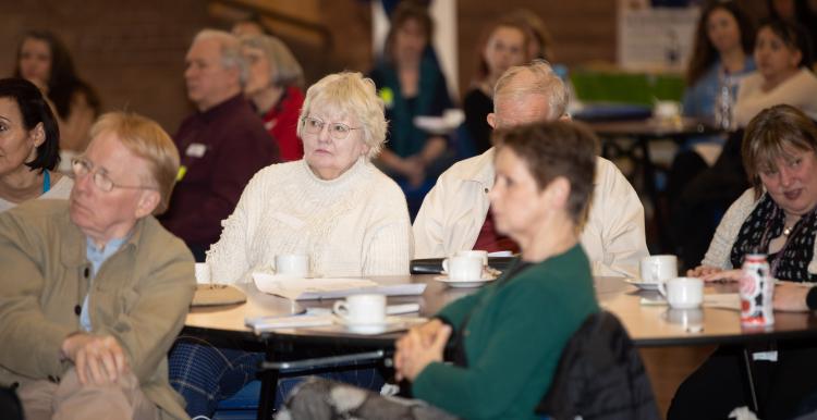 People at a meeting all looking in the same direction as though listening to someone speak or present
