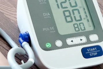 A blood pressure monitor showing a reading of 120 over 80.