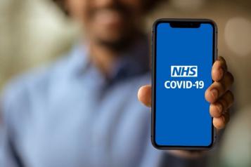 Man holding phone displaying Covid-19 app