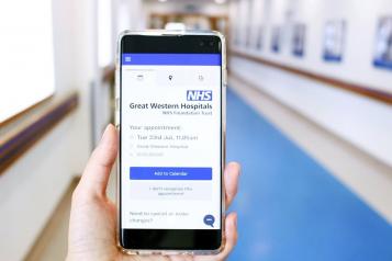 Picture of a hand holding a phone showing Great Western Hospital online booking tool