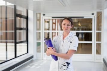 Nurse with a clipboard standing in a hospital corridor