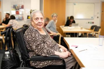 Photo of an elderly woman in a wheelchair looking directly at the camera