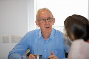 Picture of an older gentleman sitting down looking as though he is talking to somebody across a table