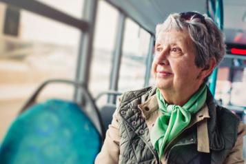 Elderly woman sitting on a bus looking out the window