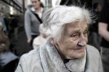 Close up of an elderly woman in a wheelhchair outside looking away from the camera