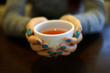Close up of a two hands holding a hot cup of tea